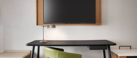 A modern office space with a large blackboard, a desk, a green chair, and a small stool.