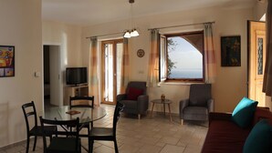 A living room with a dining area, a TV, and a sofa. - Olive Stonehouse Orestis (Kalamata)