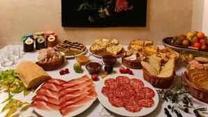 Una mesa con diferentes alimentos, como pan, bollería y embutidos.