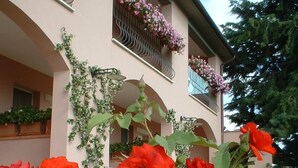 Un edificio con jardín delantero, con flores rojas y plantas verdes.