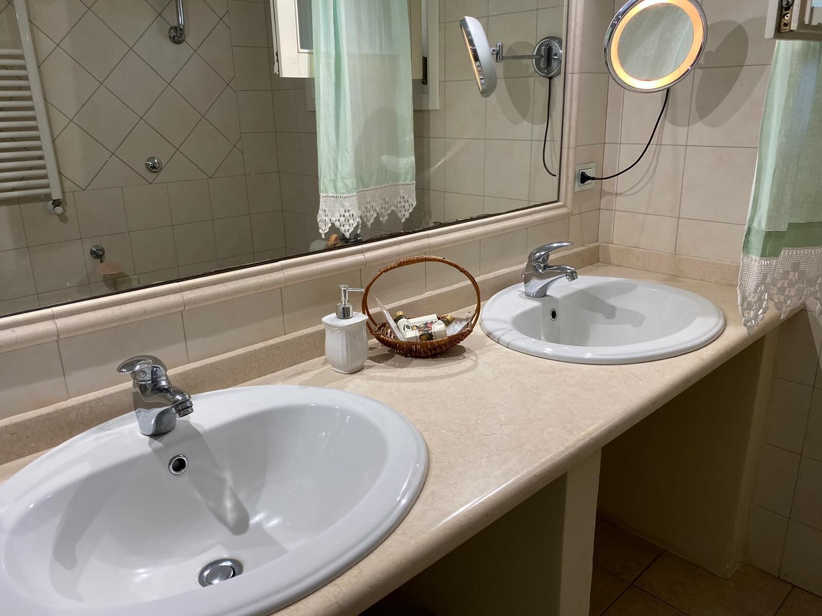 Ein Badezimmer mit zwei Waschbecken, einem Spiegel, einem Handtuchhalter und einer Duschkabine.