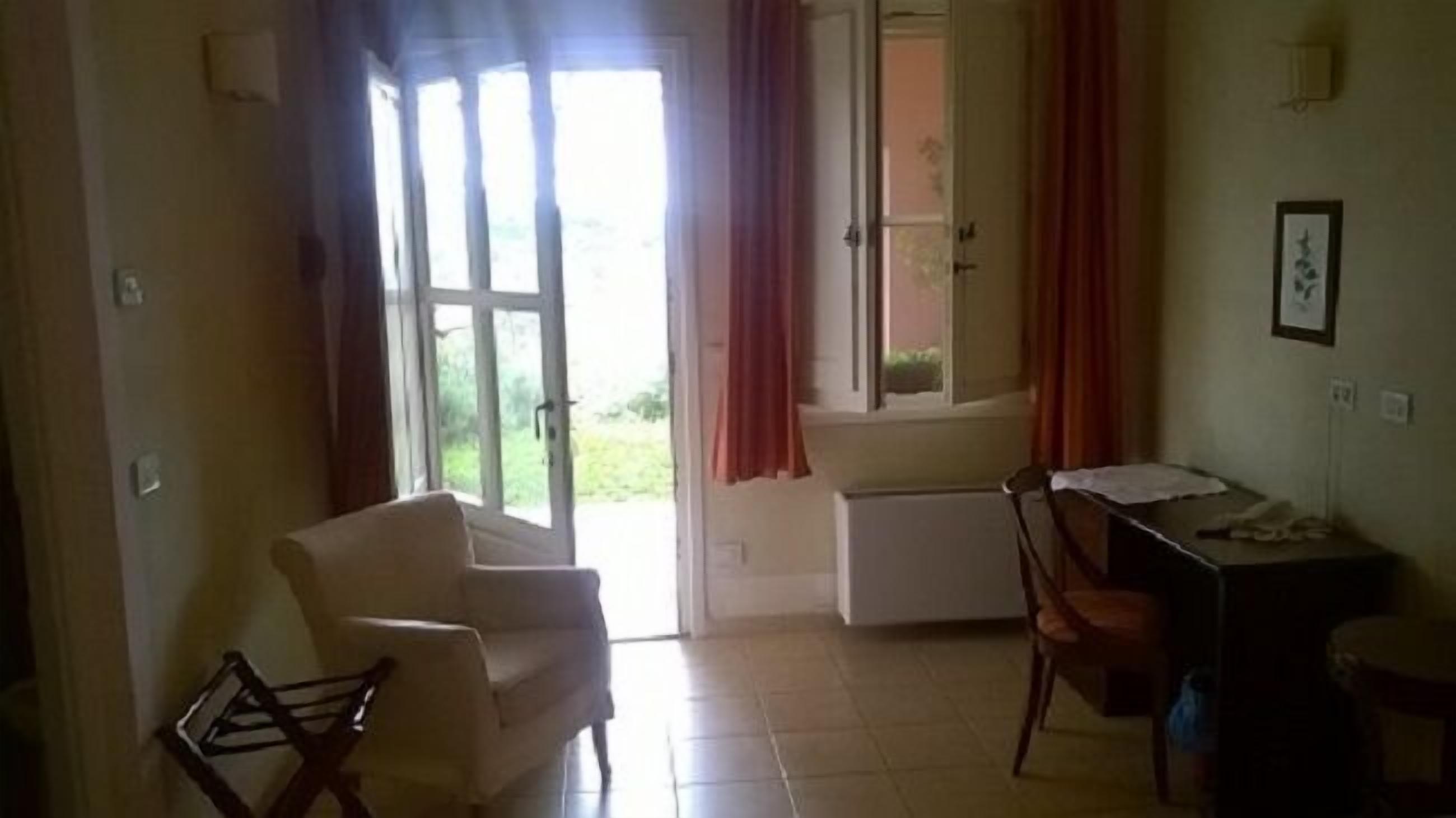 Una habitación con una silla, un escritorio y una ventana con cortinas.