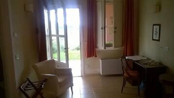 Una habitación con una silla, un escritorio y una ventana con cortinas.