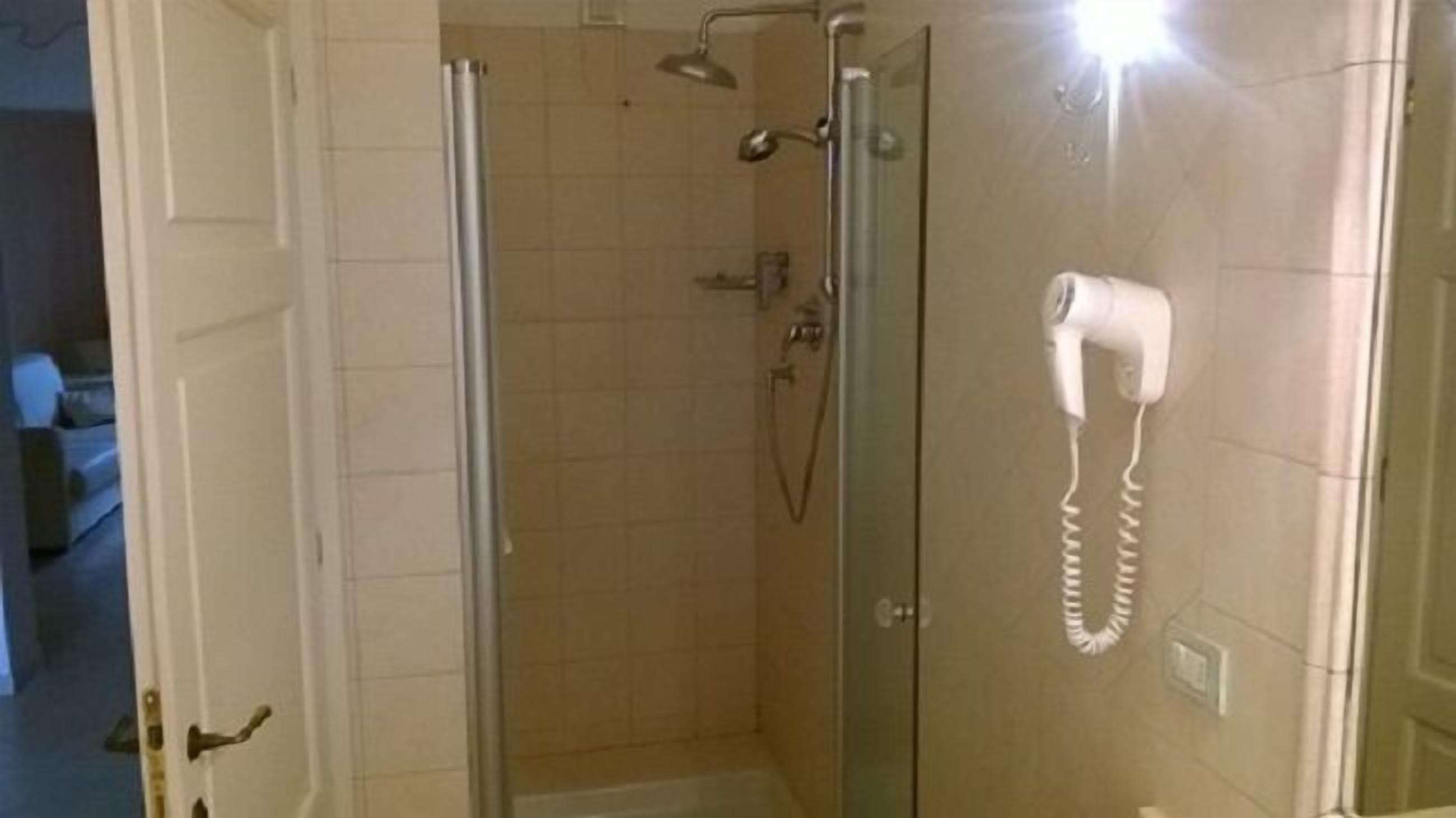 A glass-enclosed shower area with a handheld hair dryer mounted on the wall.