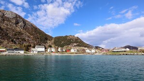 A coastal town with buildings along the shoreline, a mountain in the background, and calm water in the foreground. - Havly Bed & Breakfast (Bremanger)