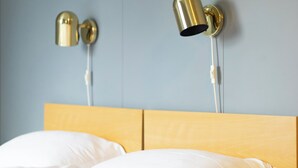A bed with white bedding and a wooden headboard, two wall-mounted lamps, and a plain wall. - Havly Bed & Breakfast (Bremanger)