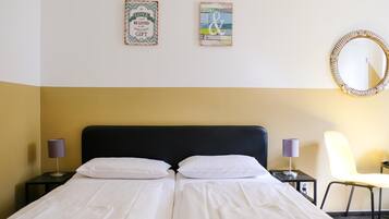 Ein Doppelbett mit weißen Bettwäsche, zwei Nachttische mit Lampen, ein Sessel und zwei Wandbilder.