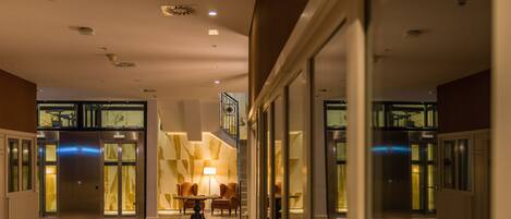 Un hall d’hôtel moderne avec un escalier, des ascenseurs et un espace salon.