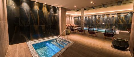 A modern spa area with a hot tub, lounge chairs, and a pool.