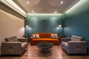 Una habitación con un sofá, dos sillones, una mesa de centro y dos lámparas de pie.