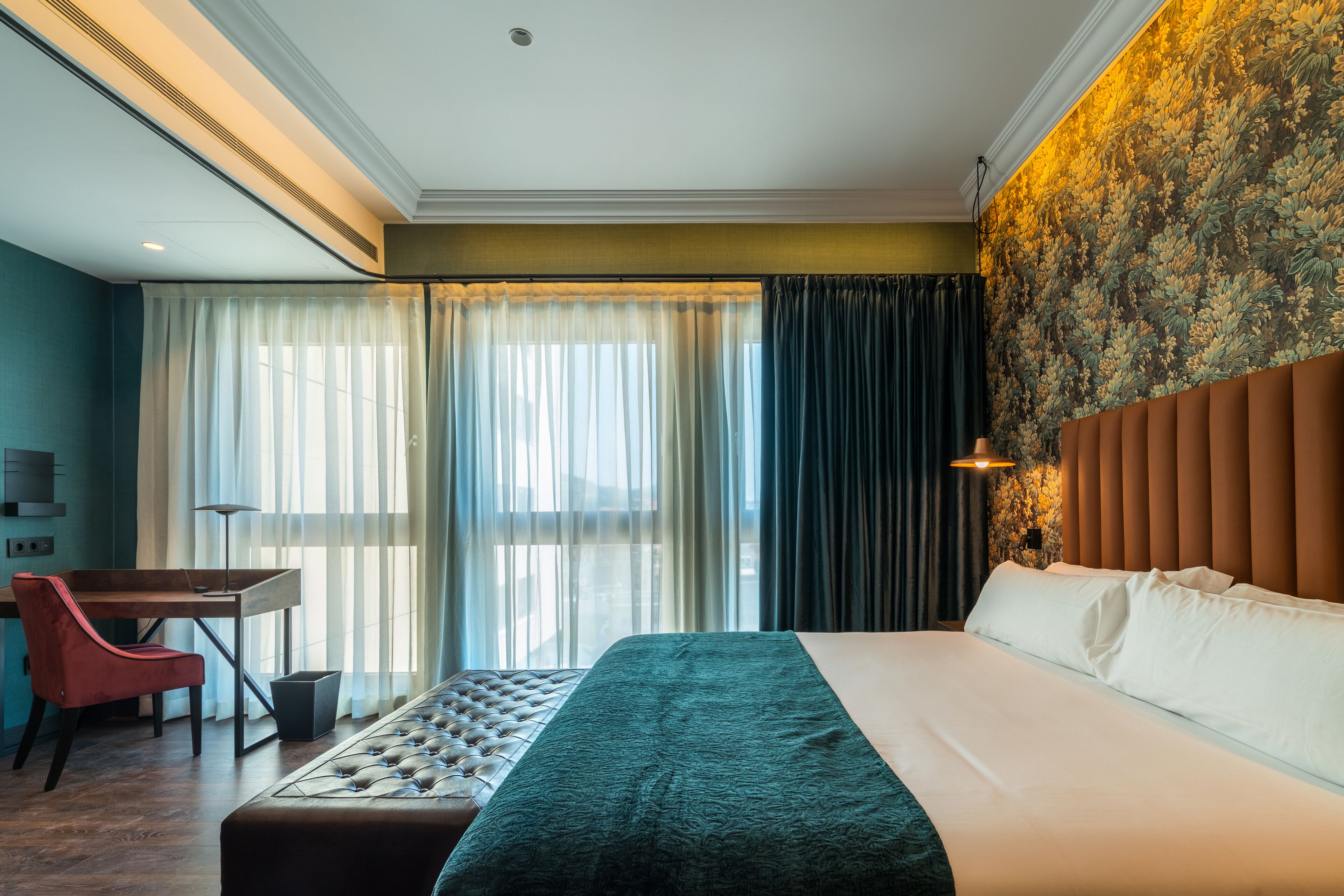 Une chambre d’hôtel avec un grand lit, un bureau, une chaise et une vue sur l’extérieur par la fenêtre.