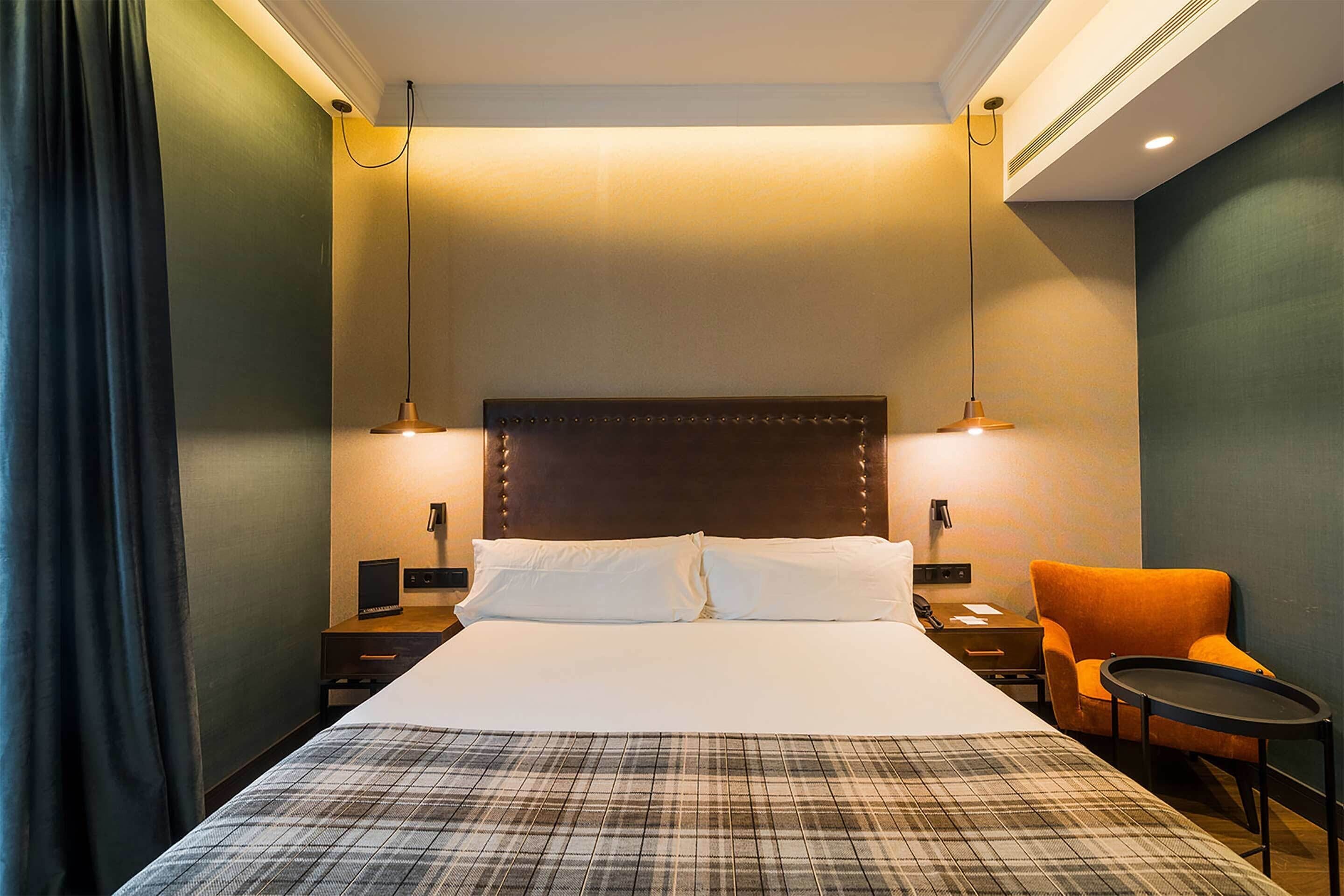 A hotel room with a large bed, two bedside tables, a chair, and a small table.
