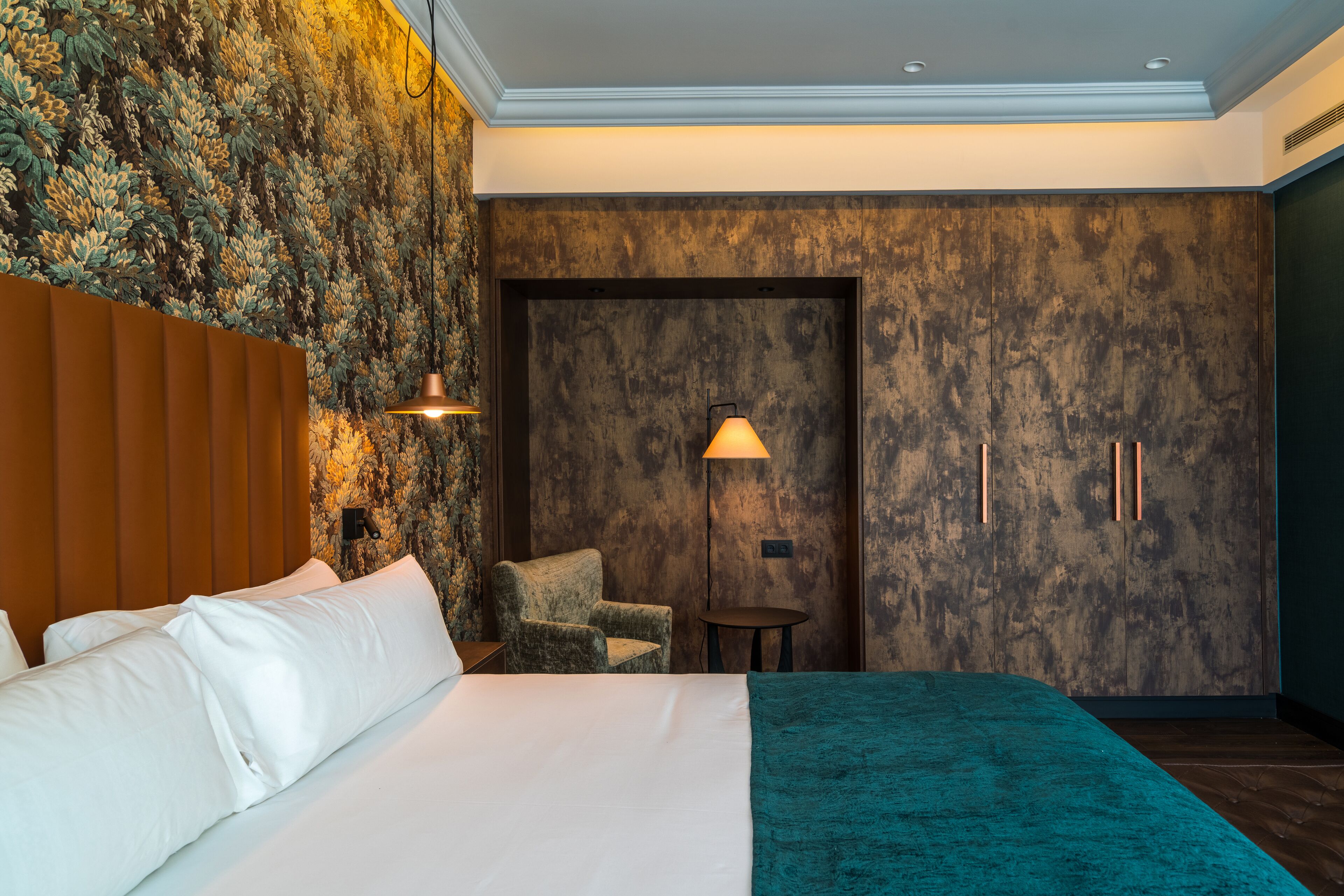 Una habitación de hotel con una cama grande, una silla, una mesita y un armario.