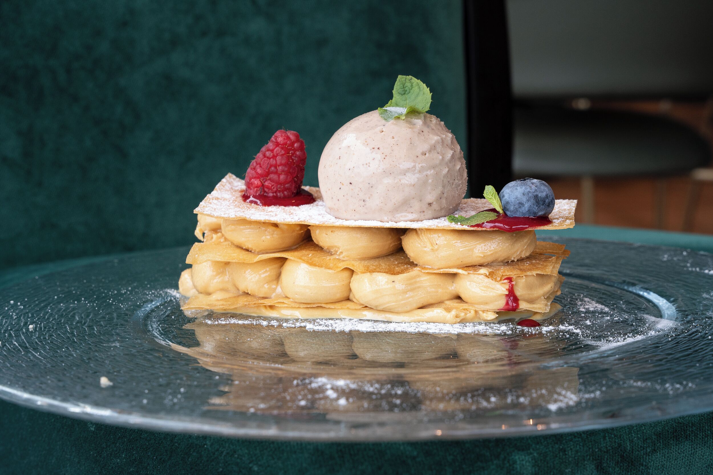 A dessert on a clear glass plate with a green background.
