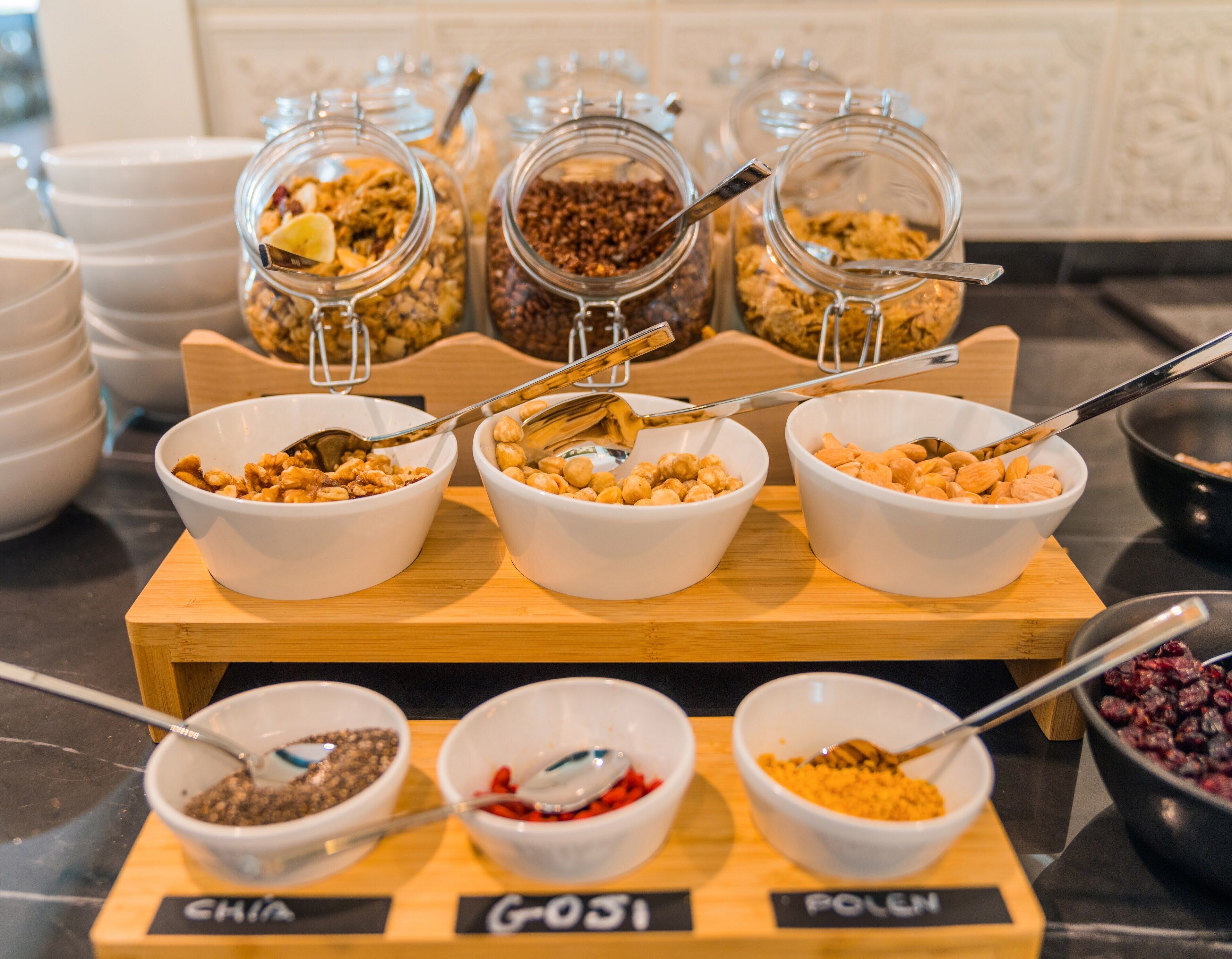 A breakfast buffet with various food options in bowls and jars, labeled with names like "CHIA" and "POLEN".