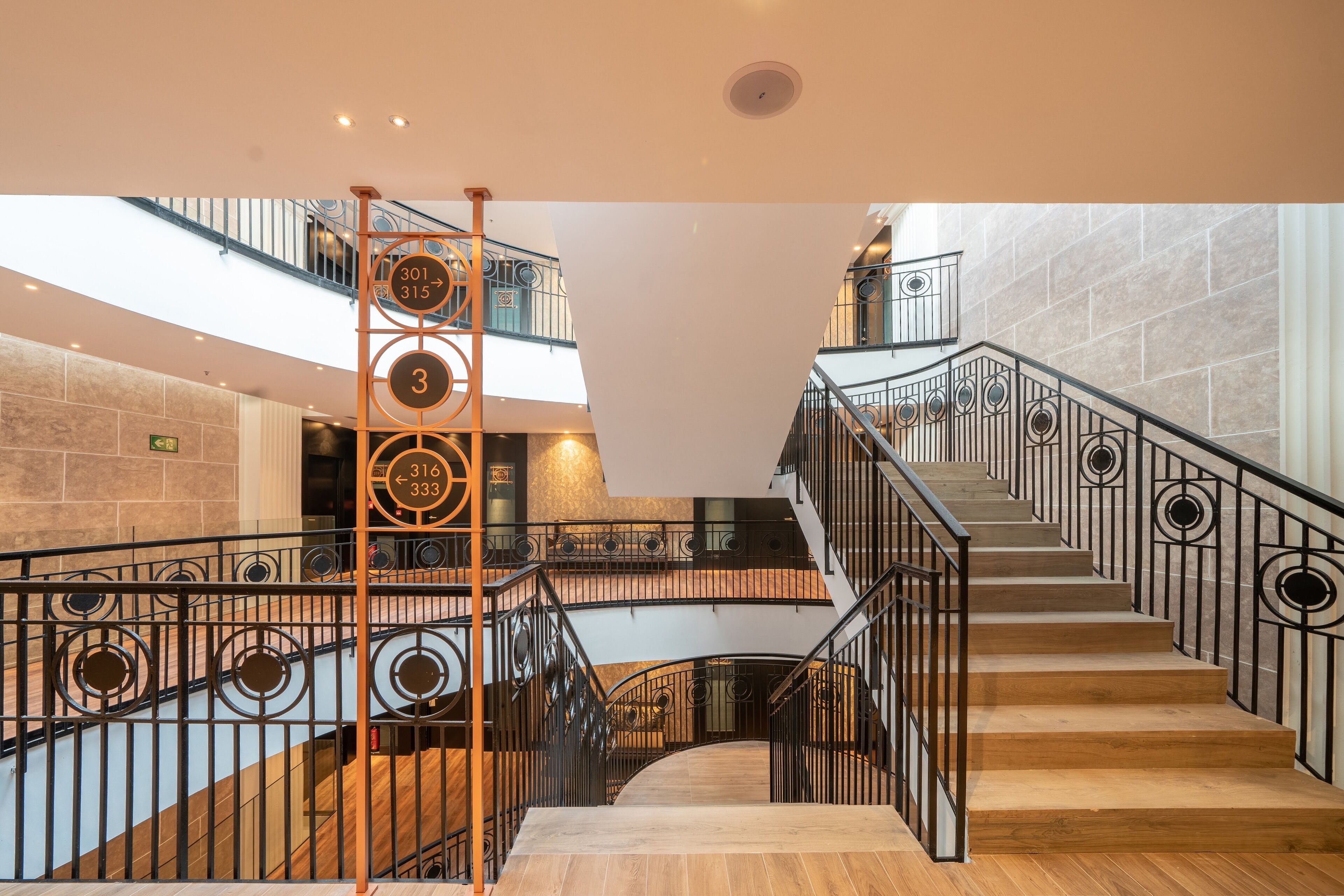 A multi-level interior with a central staircase, metal railings, and a stone wall.
