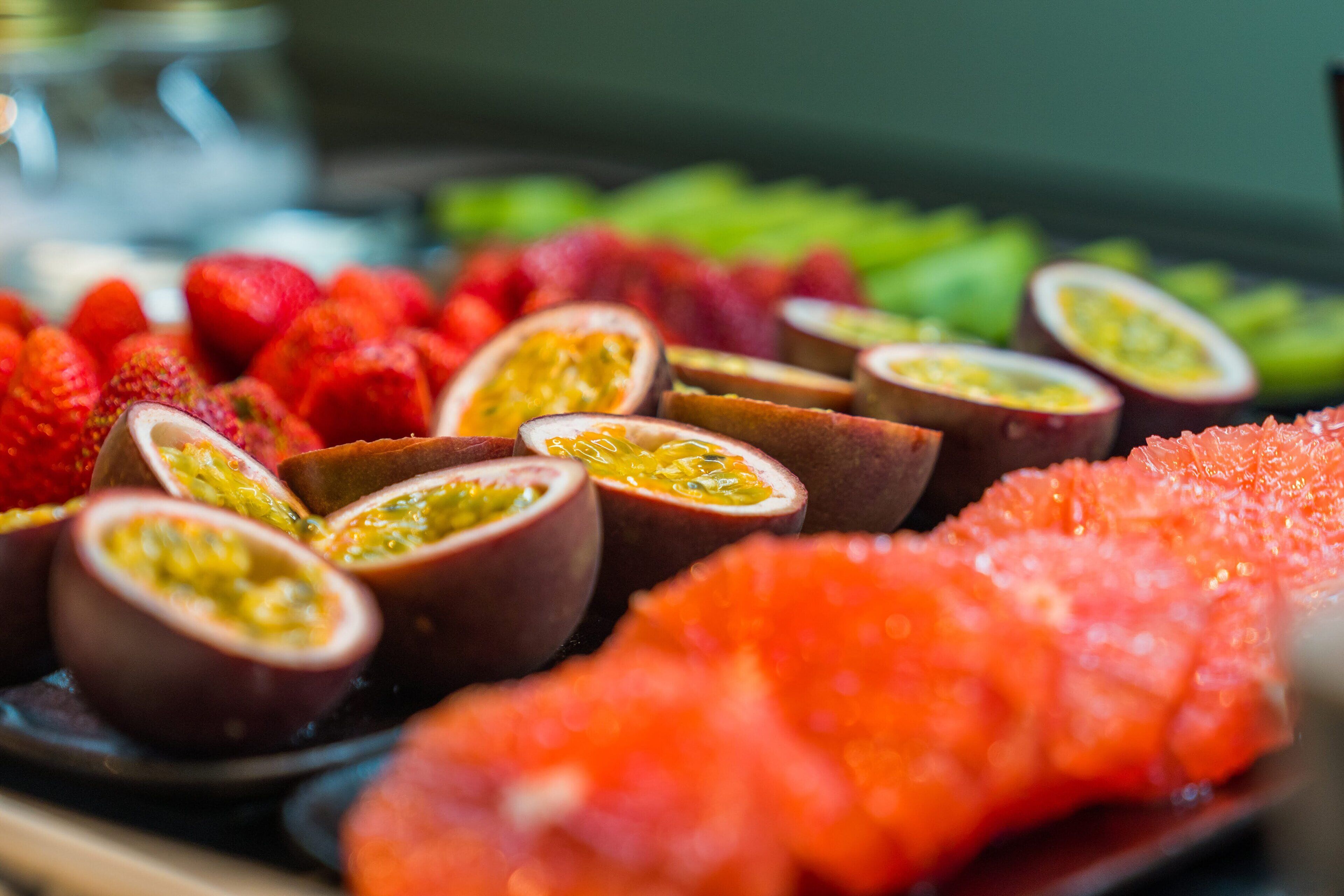 Een verscheidenheid aan gesneden fruit, waaronder aardbeien, passievrucht en watermeloen, op een schaal.
