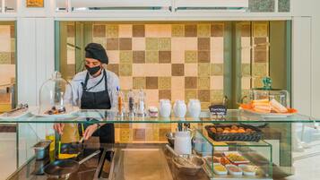 Un bufé de desayuno con un chef preparando comida, una variedad de platos y un salpicadero de azulejos.