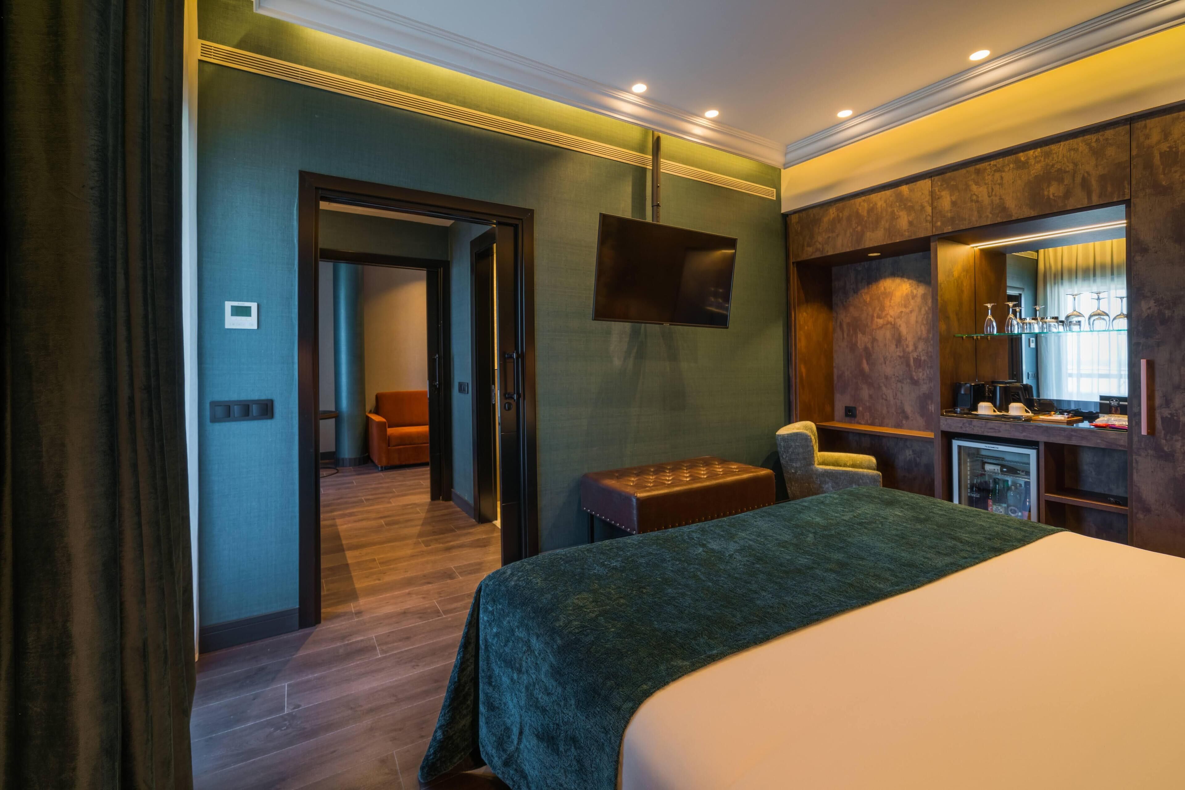 Une chambre d’hôtel comprenant un lit, un coin salon, une télévision et un minibar.