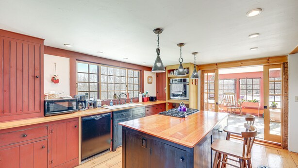 A kitchen with wooden cabinets, a large island, and a bar area with stools. - Charming Lovell Farmhouse - 17 Acres w/ Mtn Views! (Lovell)