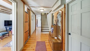 A hallway with wooden floors, a bench, a staircase, and a door with a coat rack. - Charming Lovell Farmhouse - 17 Acres w/ Mtn Views! (Lovell)
