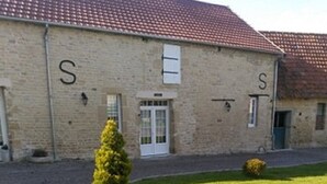 A building with a tiled roof and a small lawn area with a trimmed bush. - 5/8 person gîte close to the landing beaches (Moulins en Bessin)