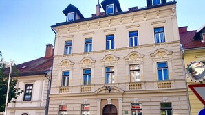 A historic building with a symmetrical facade, multiple windows, and a central entrance with a decorative arch. - Ljubljana centre, river view, balcony & bikes (Ljubljana)