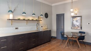 A modern kitchen with dark cabinetry, a marble countertop, and pendant lighting. - Ljubljana centre, river view, balcony & bikes (Ljubljana)