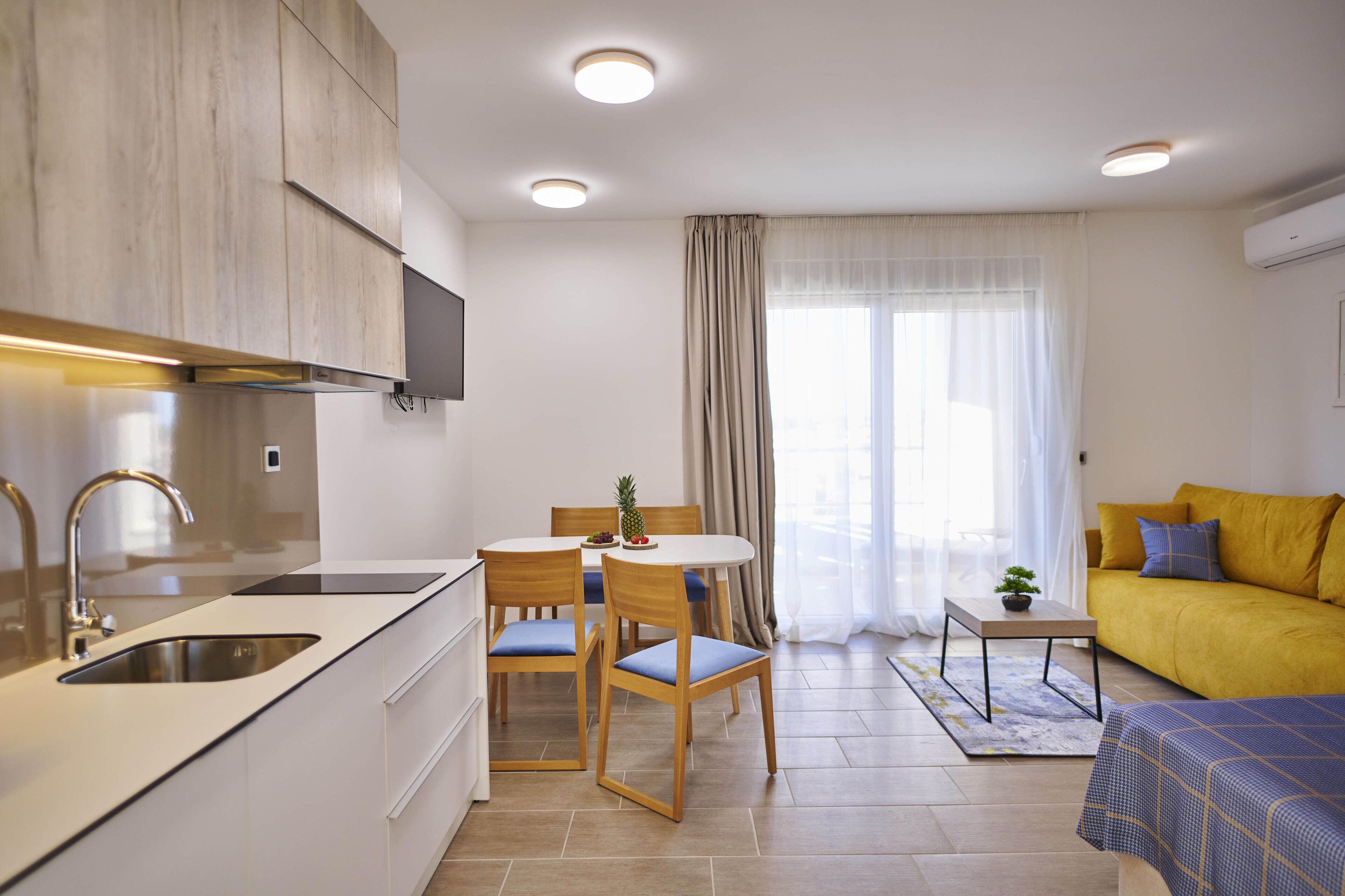 Un espacio habitable compacto con kitchenette, comedor y sofá.