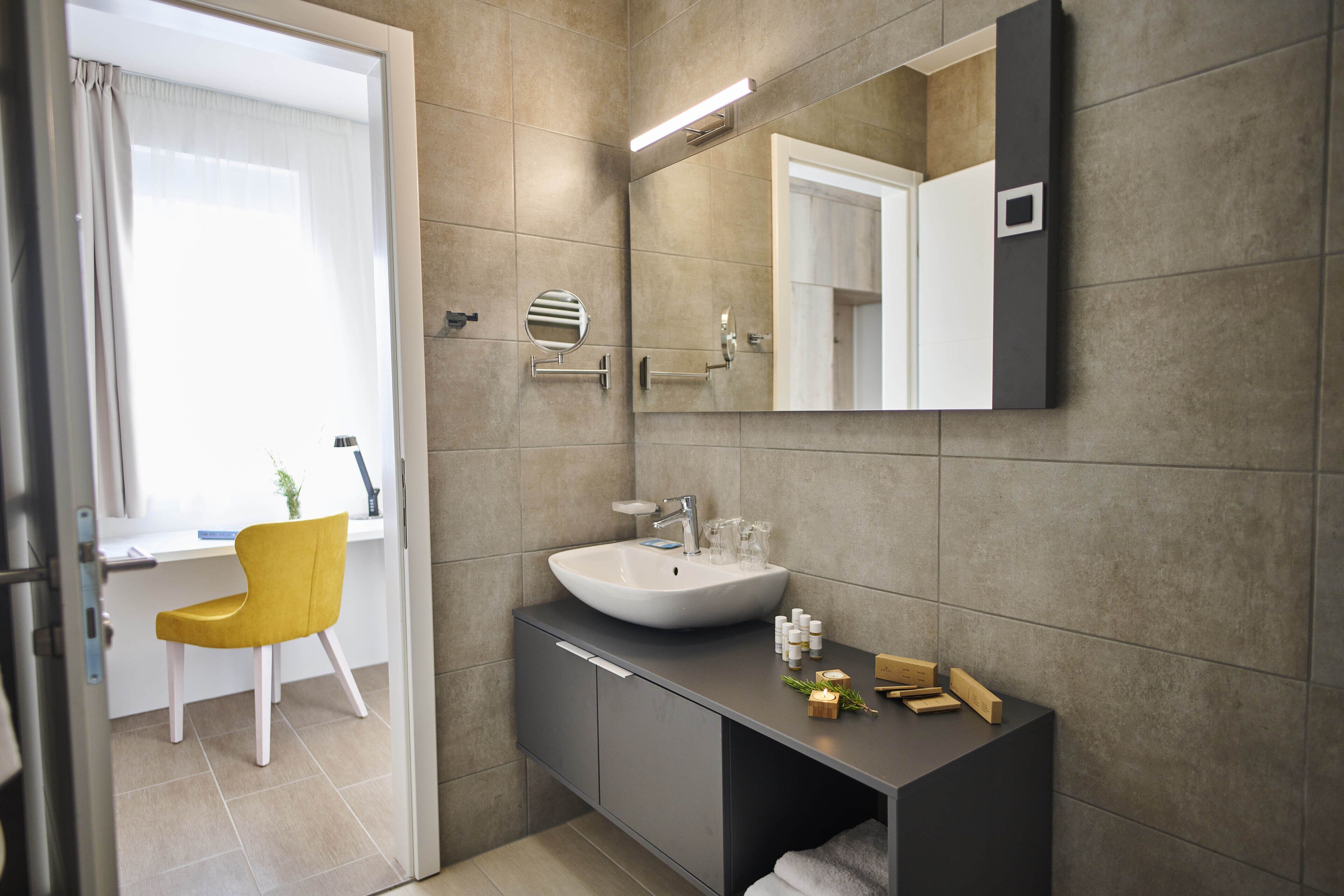 Un bany modern amb un mirall gran, un lavabo i una cadira.