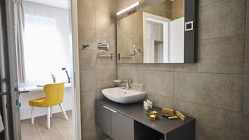 Un bany modern amb un mirall gran, un lavabo i una cadira.