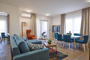 Una sala de estar moderna con un sofá, sillas, una mesa de centro y un comedor con mesa y sillas.