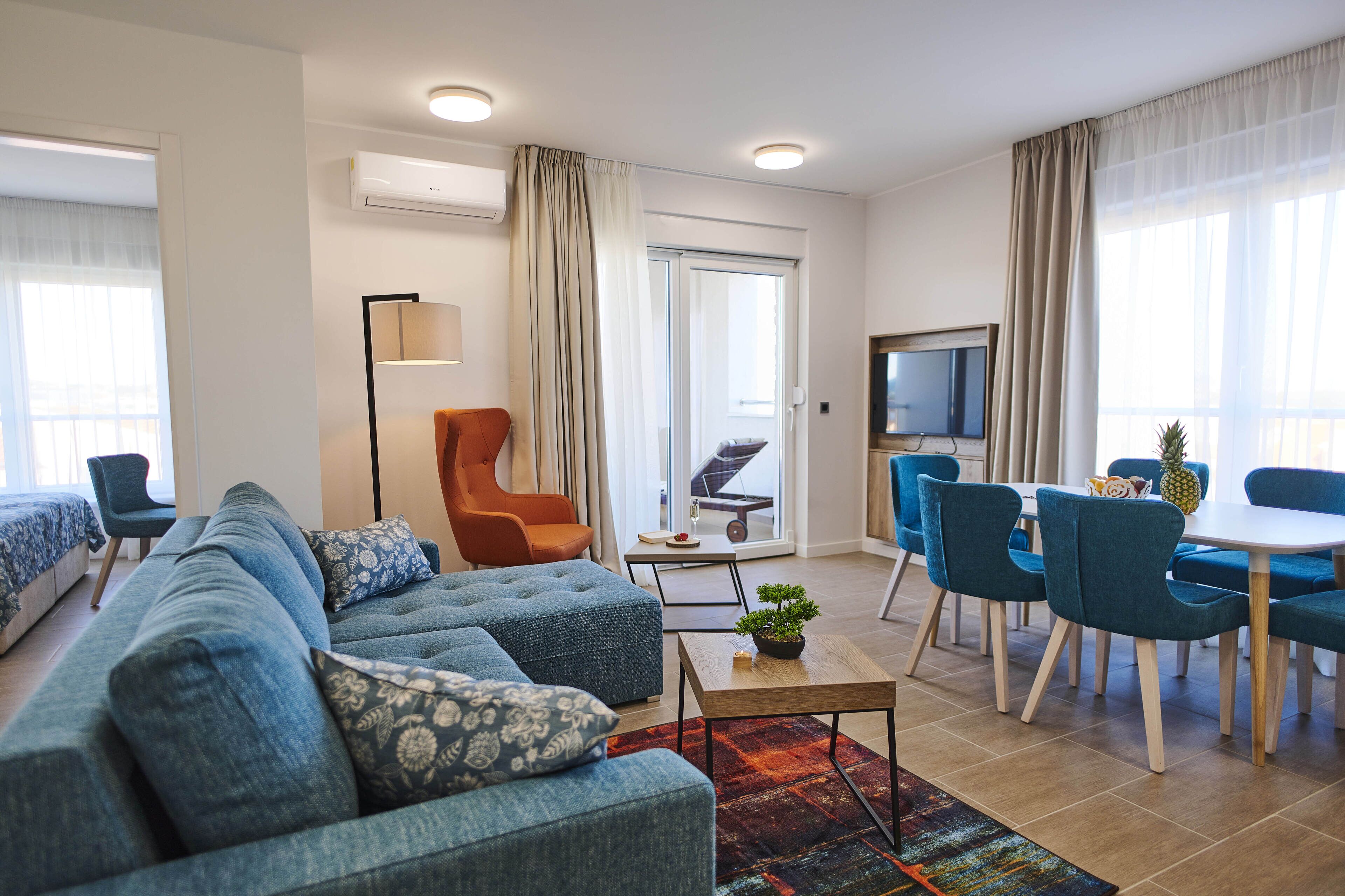 A modern living room with a sofa, armchairs, a coffee table, and a dining area with chairs and a table.