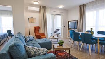 A modern living room with a sofa, armchairs, a coffee table, and a dining area with chairs and a table.