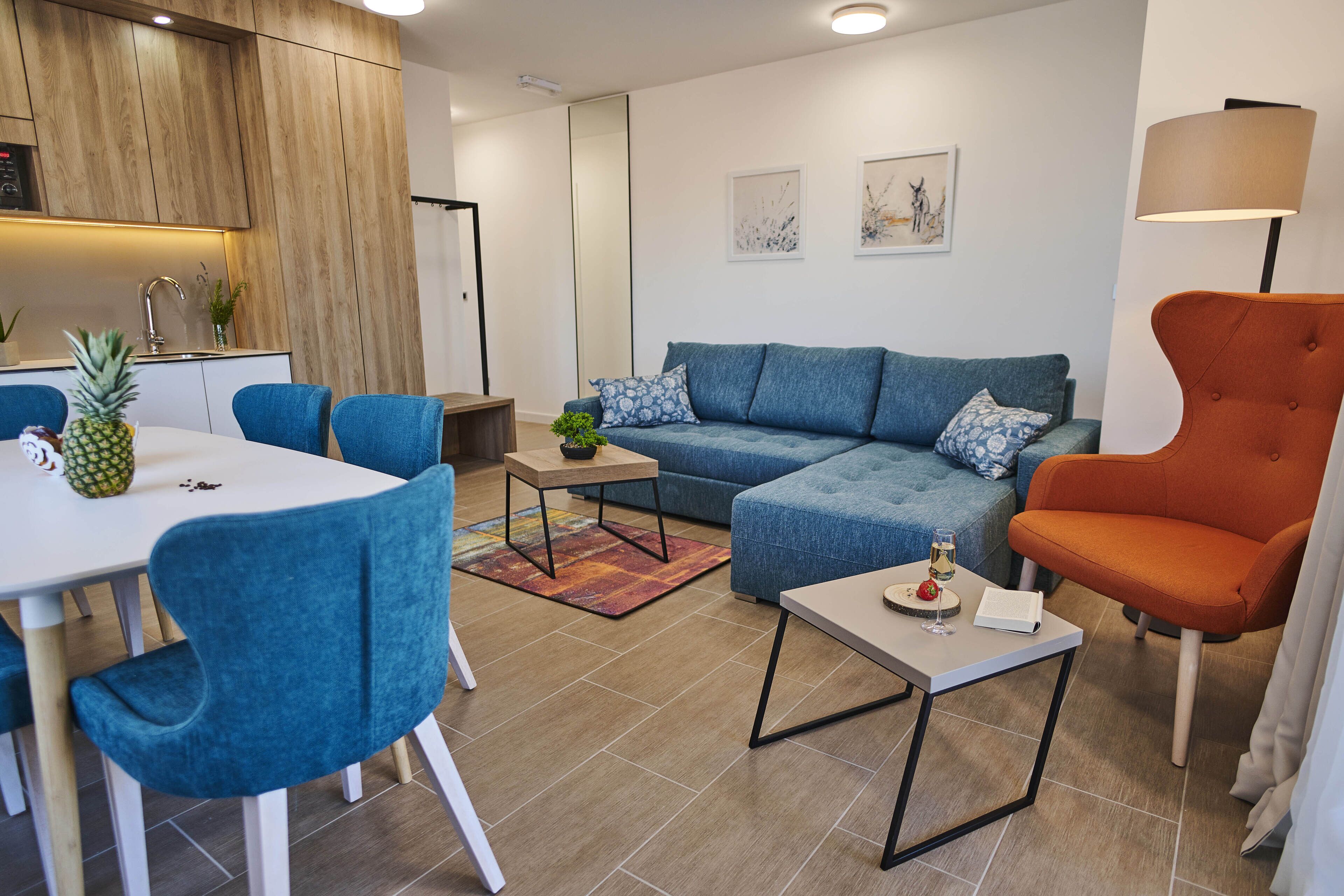 A modern living room with a sofa, chairs, a coffee table, and a dining area with a table and chairs.