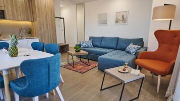 A modern living room with a sofa, chairs, a coffee table, and a dining area with a table and chairs.