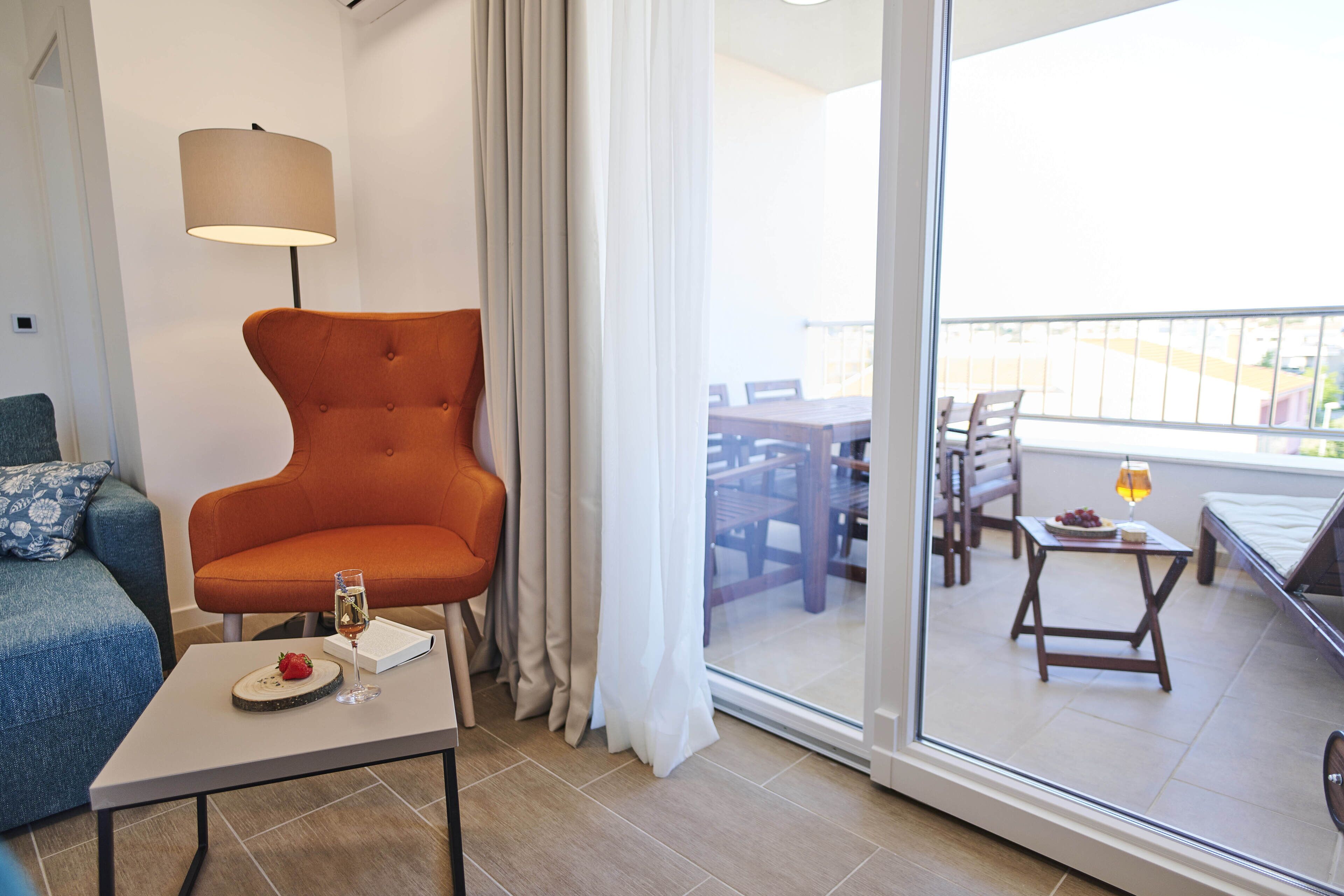 Una sala de estar moderna con un sofá, una mesa con una copa de vino y una silla.
