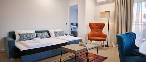 A modern hotel room with a bed, a desk, a chair, and a view of the outside.