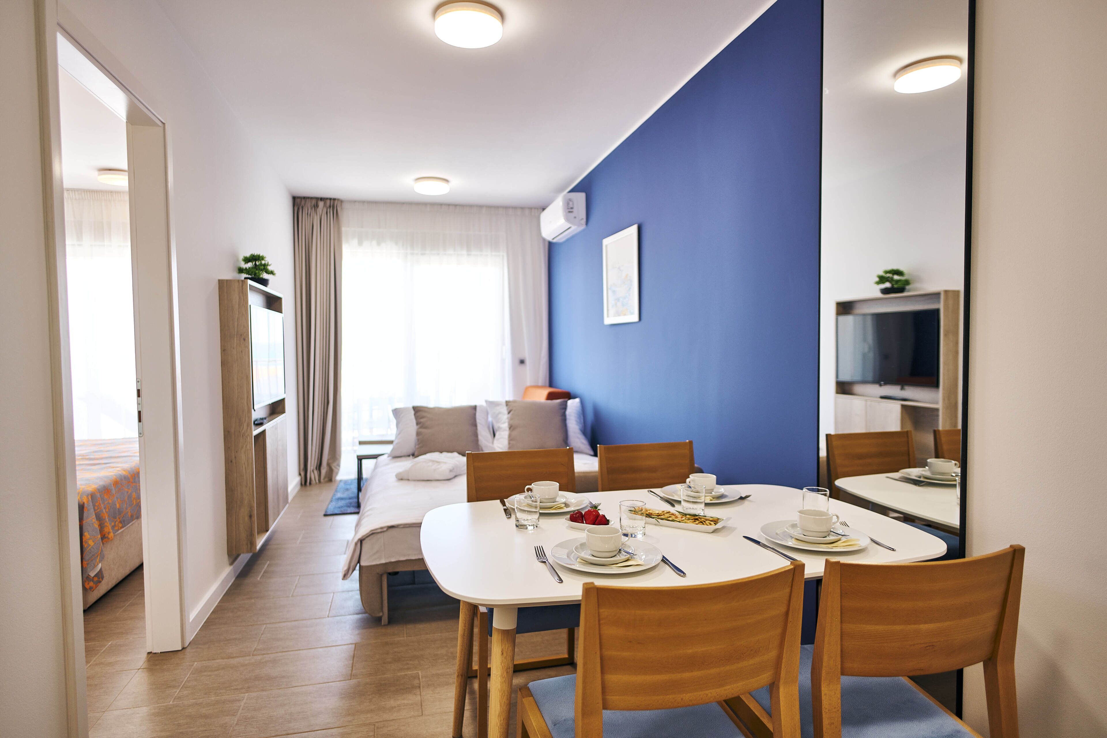 A hotel room with a dining area, a bed, and a TV.