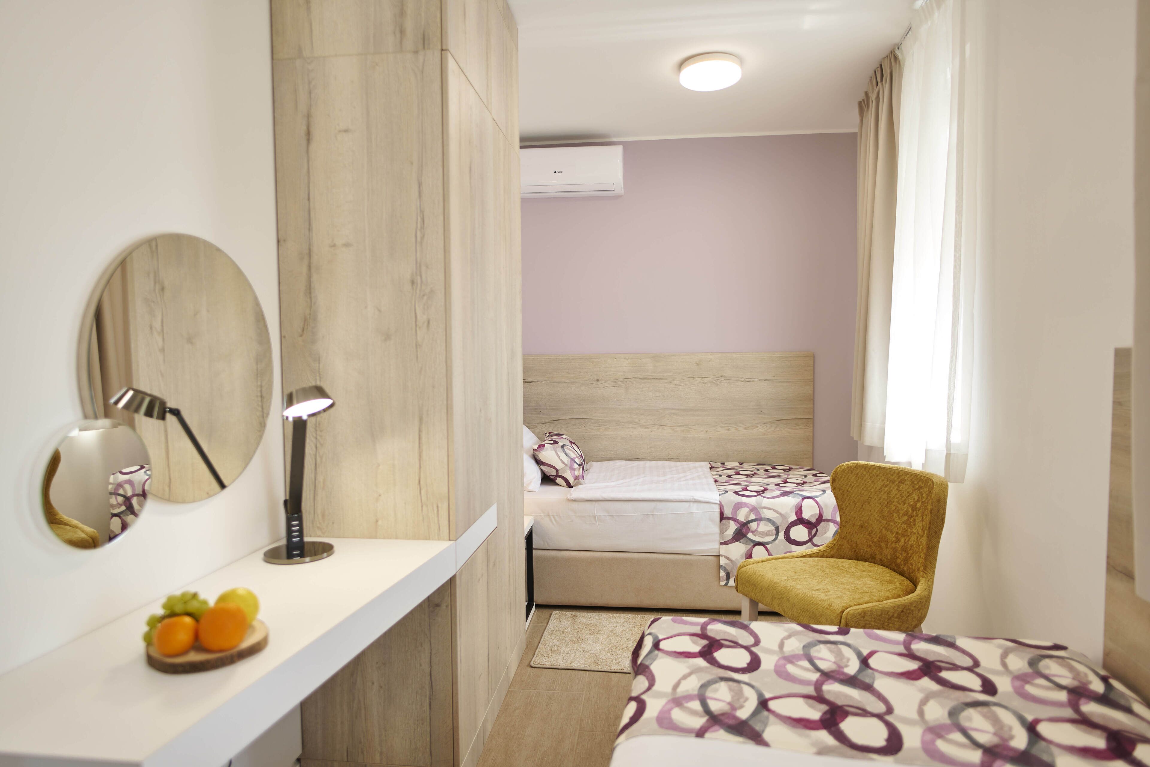 A modern bedroom with a wooden headboard, a bedside table with a lamp, and a bed with patterned bedding.