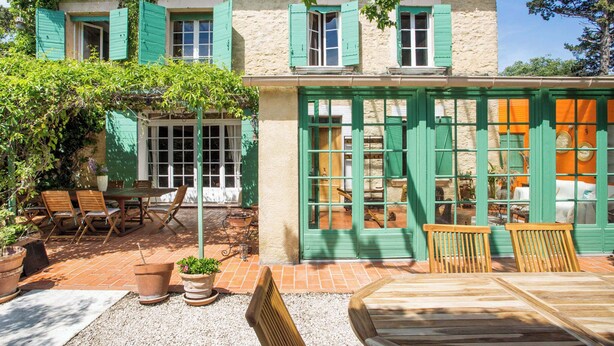 Un bâtiment de style rustique doté d’un patio aménagé avec des meubles en bois et des plantes en pot.