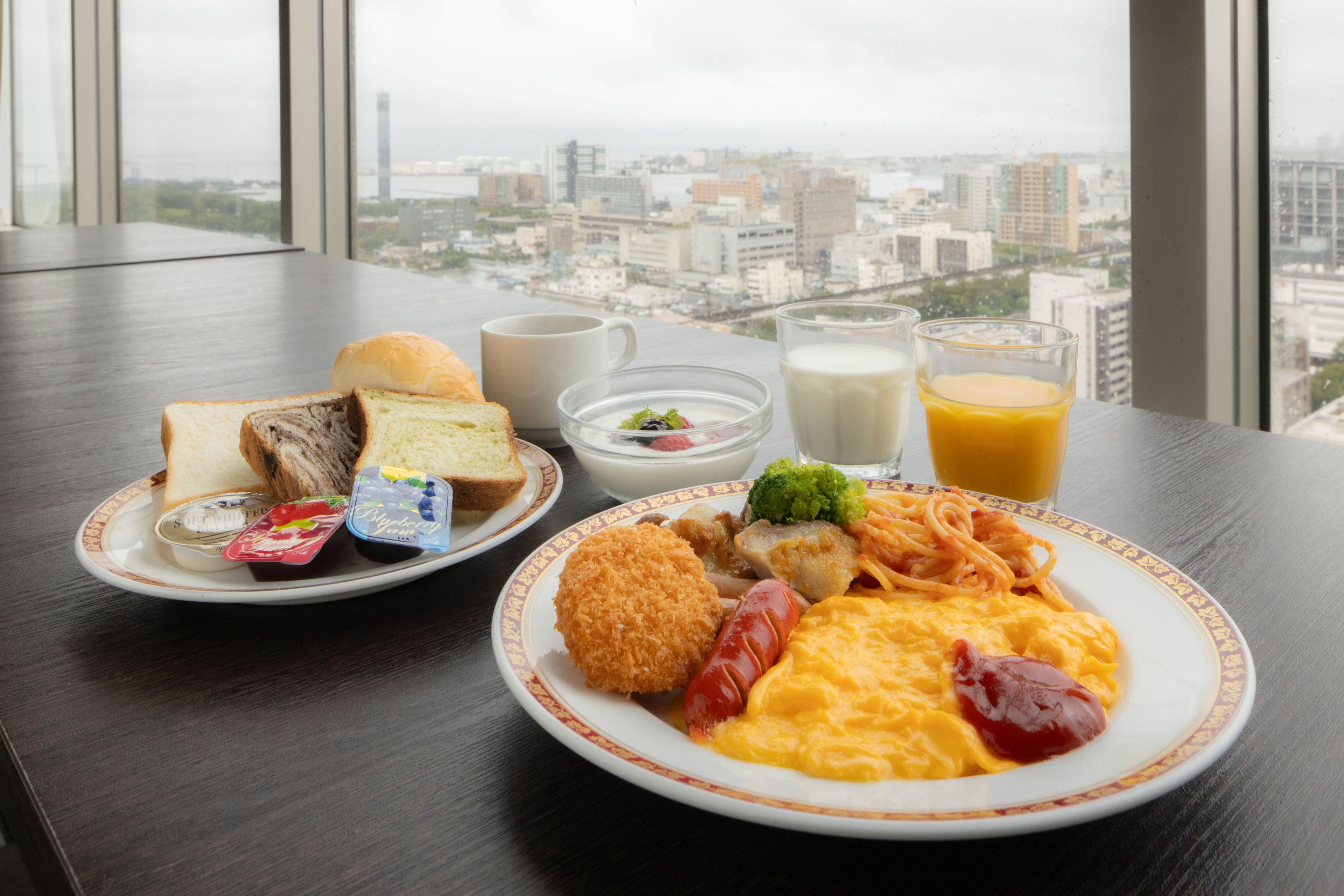 A breakfast table with plates of food, a cup, and a glass of orange juice.