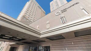 Entrada de hotel con diseño moderno, que presenta un logotipo y nombre destacados en la fachada.