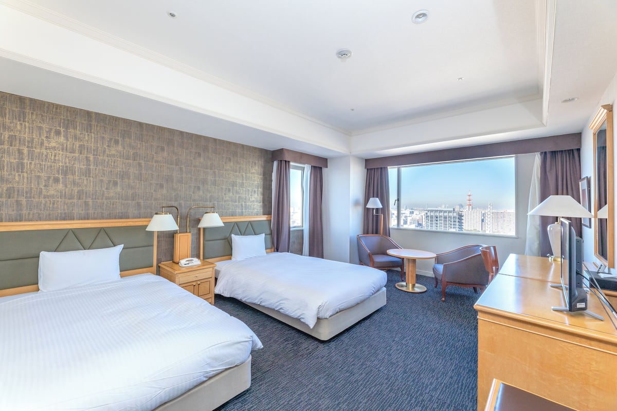Une chambre d’hôtel avec deux lits, un bureau, une chaise et une vue sur la ville.