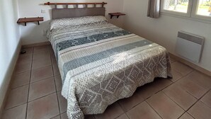 Una camera da letto con un letto, una finestra, un termosifone e una mensola a muro.