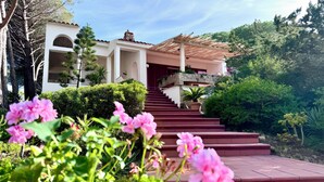 Ein mehrgeschossiges Gebäude mit roter Fassade und einer steinernen Verkleidung, mit einer überdachten Treppe zum Eingang.