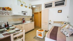 Ein kompakter Wohnbereich mit Küchenzeile, Essplatz und einem Bett.