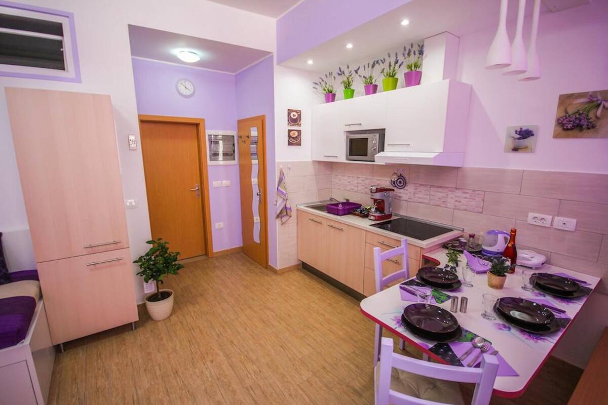 Een kleine keuken met een magnetron, spoelbak en een eethoek voor vier personen.