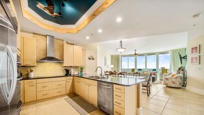 A spacious kitchen with wooden cabinets, a stainless steel range hood, and a large island with a dishwasher.