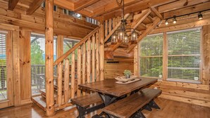 Ein Holzinnenraum mit einer Holztreppe, einem Holzespeisesaal mit Bänken und großen Fenstern mit Jalousien.